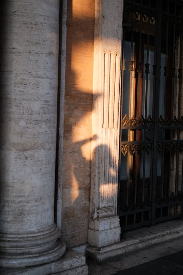 Luce e ombra della sera su colonne di pietra e un cancello in ferro battuto